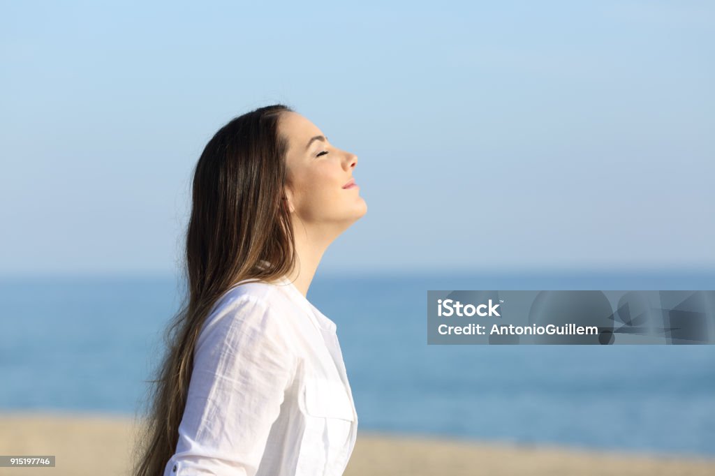 Woman relaxing breathing fresh air on the beach Side view portrait of a woman relaxing breathing fresh air on the beach Breathing Exercise Stock Photo