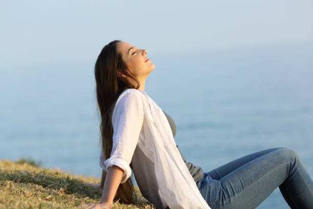 entspannte frau frische atemluft sitzen auf dem rasen - zen like nature breathing exercise sitting stock-fotos und bilder