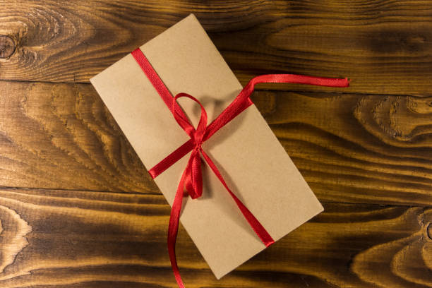 istock Cardboard gift box with red ribbon on wooden table 915198434