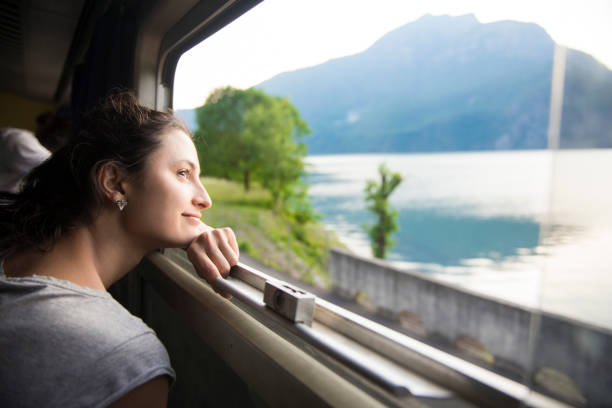 Smiling woman looking at the view from train Smiling woman looking at the view from train passenger train photos stock pictures, royalty-free photos & images