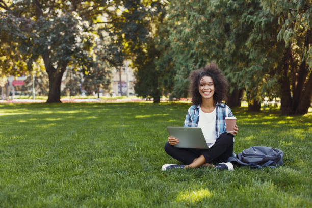 istock Cheerful young woman using laptop in park 915202908
