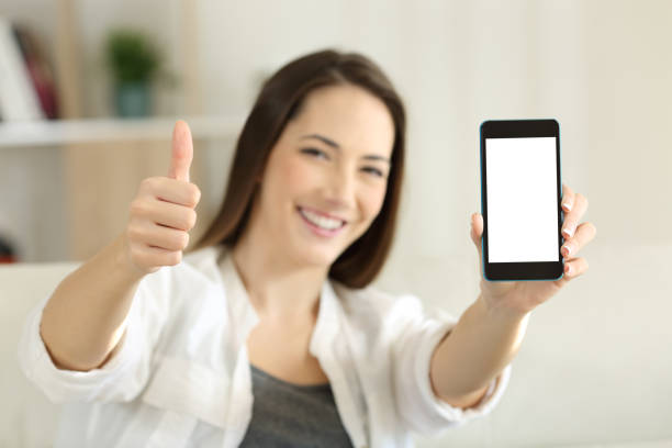 istock Female showing a blank smart phone screen at home 915206296