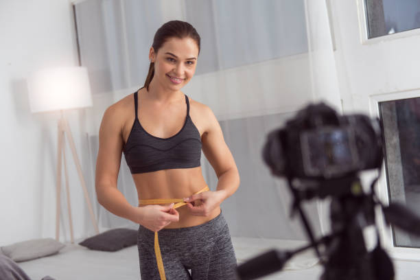 istock Happy blogger measuring her waist while making a video 915210174