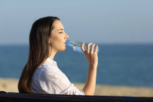 istock Woman drinking water from a bottle on the beach 915213476