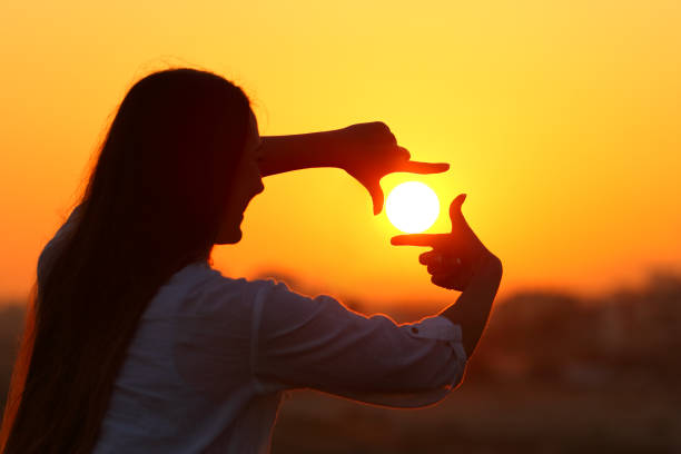 istock Woman framing sun with fingers at sunset 915213644