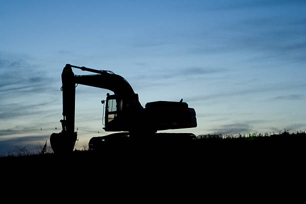 silouette of excavtor at dusk stock photo