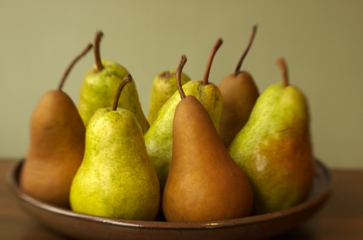 A yellow ripe pear with a red side on the table, a harvest of fresh crispy pears during cooking