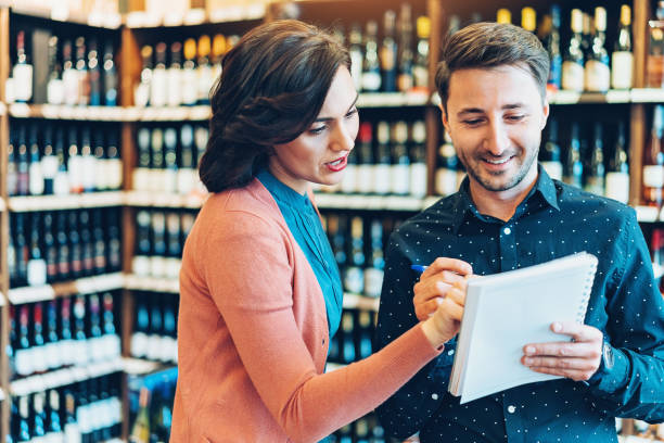 pareja trabaja en una tienda de vinos - wine cellar liquor store wine rack fotografías e imágenes de stock