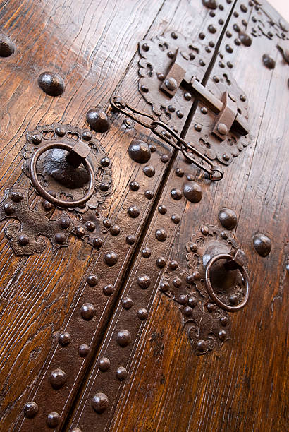 An intricate wood oak door with an old-fashioned lock in Exeter Cathedral or Cathedral Church of Saint Peter, an Anglican cathedral located in the centre of the city of Exeter, Devon, Southwest England, UK.