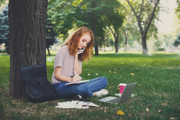 istock Young redhead student girl working sitting under a tree 915218276