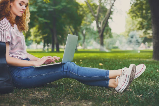istock Young redhead girl in casual working sitting under a tree 915218368