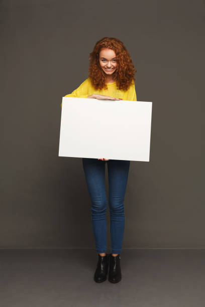 istock Young happy woman with blank white paper 915218880