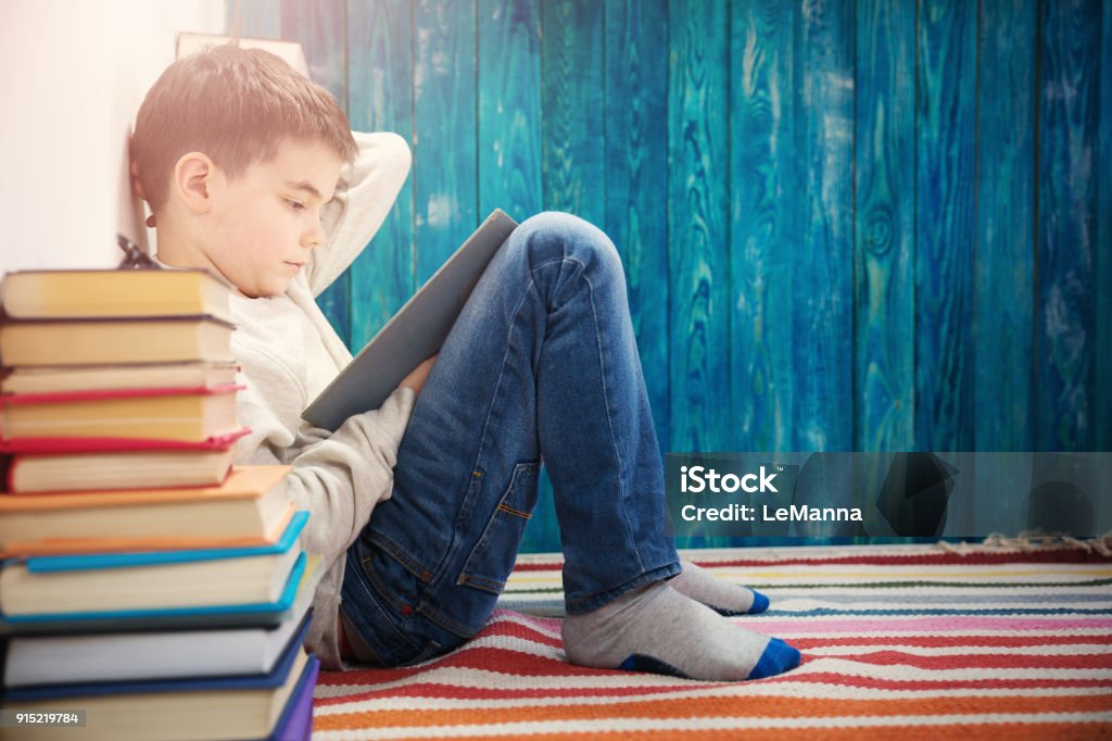 eight years old child reading a book eight years old child reading a book at home. Boy studying on blue background Child Stock Photo