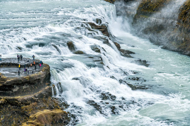 Tourists Looking at a River and its Waterfalls in Iceland.