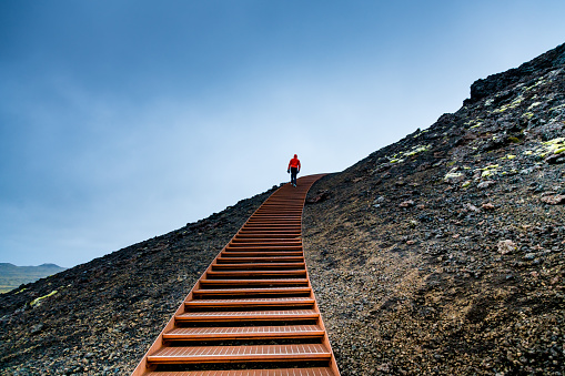 Man Walking on Stairs on a Mountain Against Blue Sky.