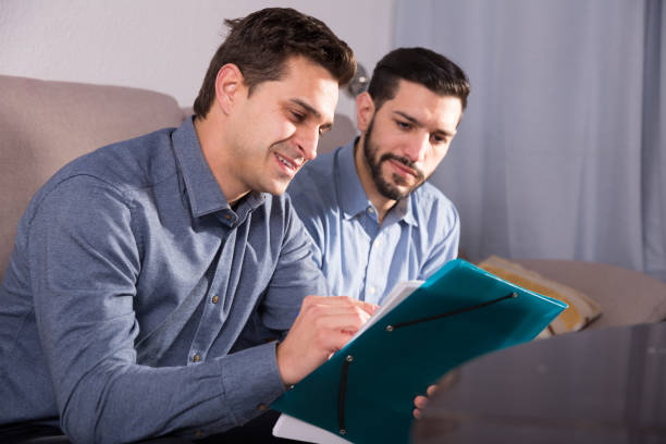 istock Two smiling friends discussing papers on couch 915222548