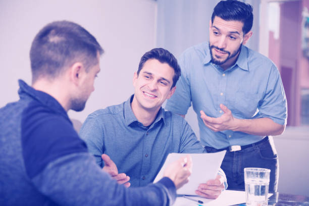istock Two positive men helping friend with documents at table 915222578
