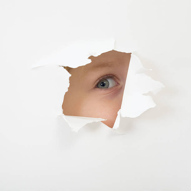 istock Eye looking through hole in sheet of paper 91522271