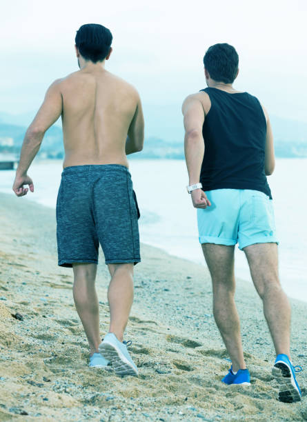 istock Two sportsmen jogging on beach 915222836