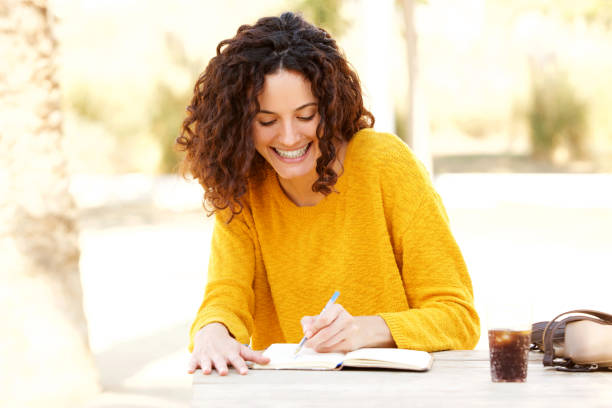 istock young woman sitting at table writing in diary 915230334