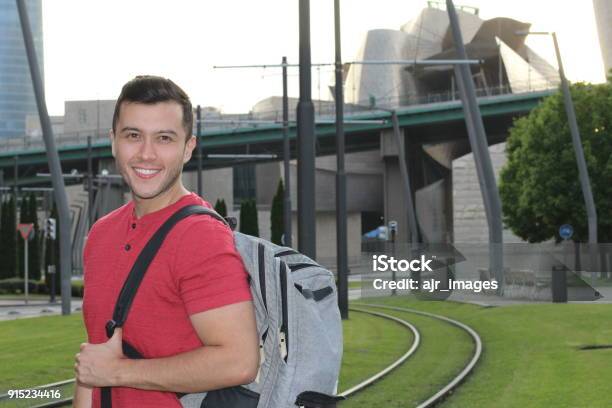 Handsome Commuter Smiling While Waiting For Train Stock Photo - Download Image Now - 20-29 Years, Adult, Backpack