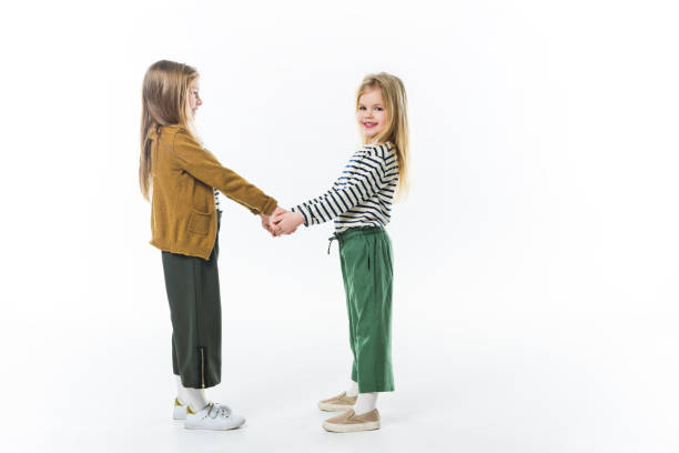 istock adorable little sisters holding hands isolated on white 915236778