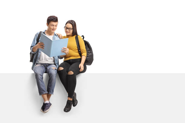 istock Teenage students seated on a panel reading a book together 915236836