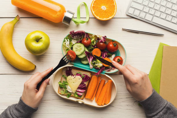 istock Woman eating healthy dinner from lunch box at her working table 915237142
