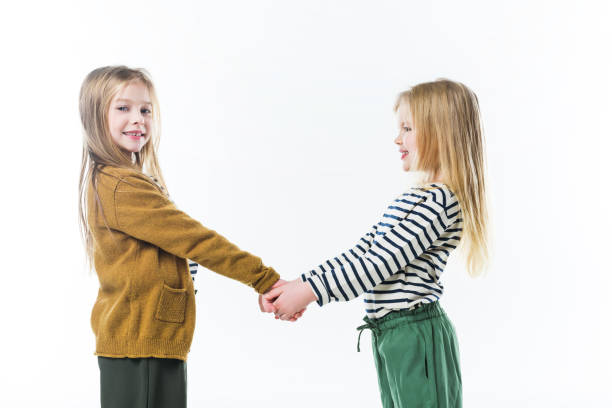 istock happy little sisters holding hands isolated on white 915237214