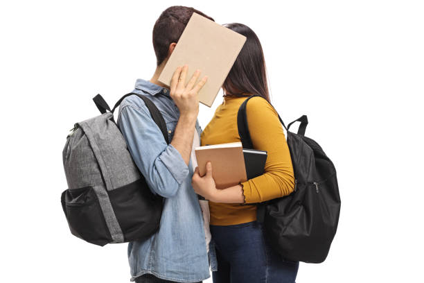 teen studenten hinter einem buch küssen - teenage couple stock-fotos und bilder