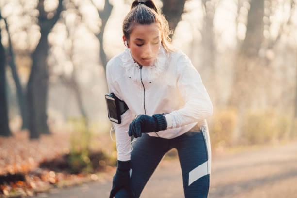 Sportswoman checking pulse Teenage girl checking heart rate on smartwatch early fall stock pictures, royalty-free photos & images