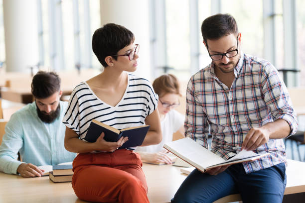 istock Young happy students sitting in library 915243878