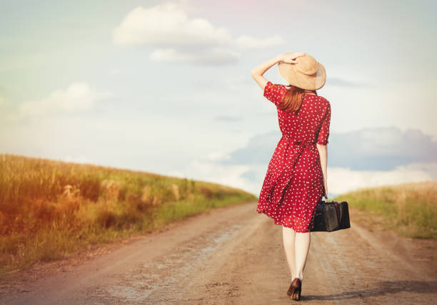 menina com bolsa andando na estrada na zona rural - polka dot suitcase retro revival women - fotografias e filmes do acervo