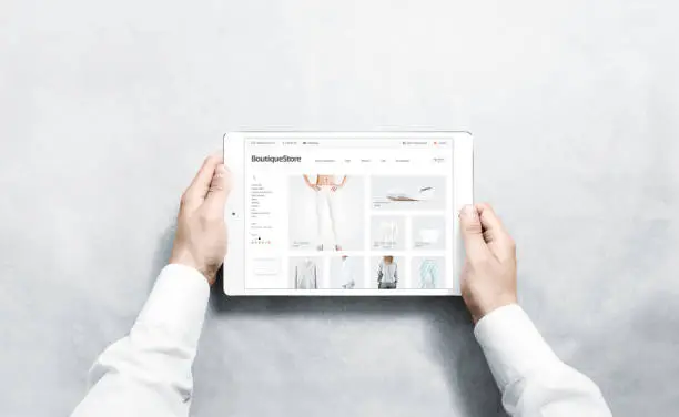 Photo of Hands holding tablet with fashion webstore mock up on screen