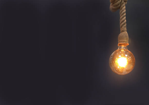 istock Lightbulb hanging in front of dark background 915254324