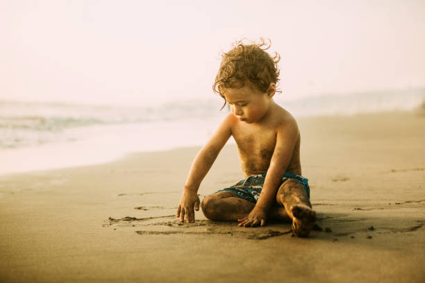 istock Boy playing in sand at the beach 915256136