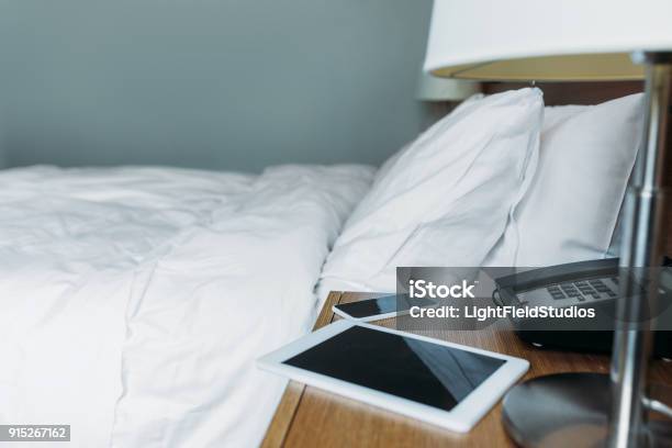 Smartphone And Tablet On Bedside Table In Hotel Room Stock Photo - Download Image Now