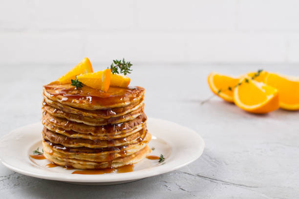 colazione o brunch fatti in casa: pancake in stile americano serviti con sciroppo di caramello arancione e cosparso - honey caramel syrup fruit foto e immagini stock