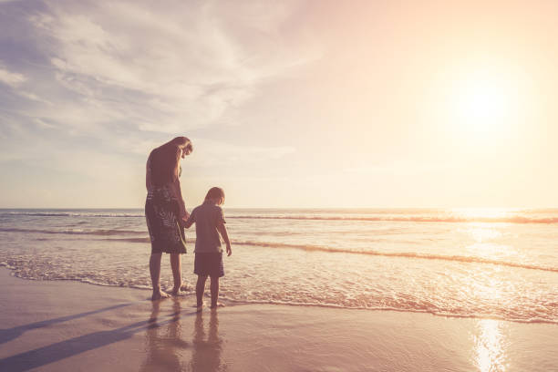istock Mother playing with her son on the beach at the sunset time 915267376