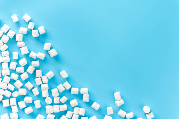 istock Marshmallows on blue background with copyspace. Flat lay or top view. Background or texture of colorful mini marshmallows. Winter food background concept. 915274450