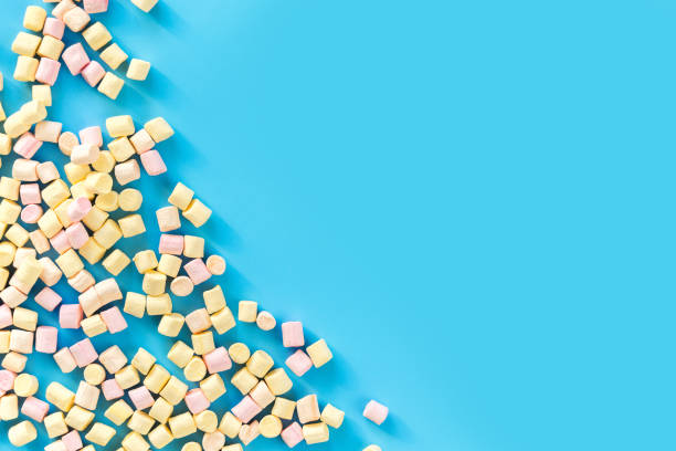istock Marshmallows on blue background with copyspace. Flat lay or top view. Background or texture of colorful mini marshmallows. Winter food background concept. 915274634