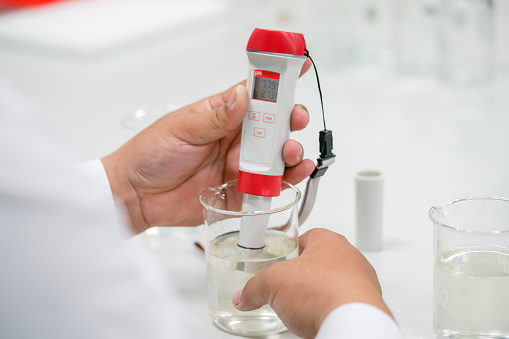 The scientist work at the chemical solution with handle pH meter in the laboratory