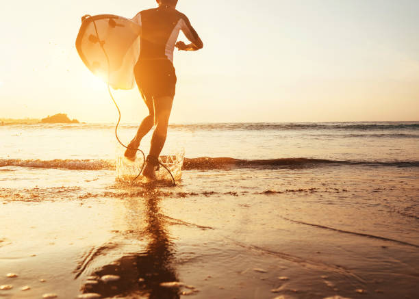istock Man surfer run in ocean with surfboard in sunset light 915276674