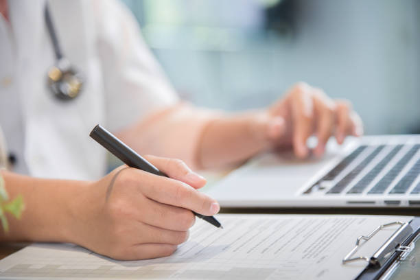 istock female doctor is using laptop and writing something on clipboard. 915280720