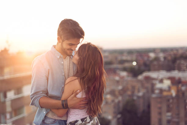 istock Couple in love on a building rooftop at sunset 915288778