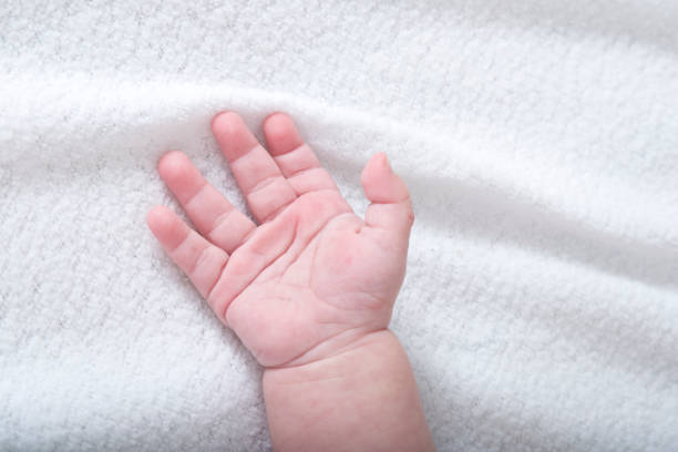 Beautiful baby hand on white soft blanket
