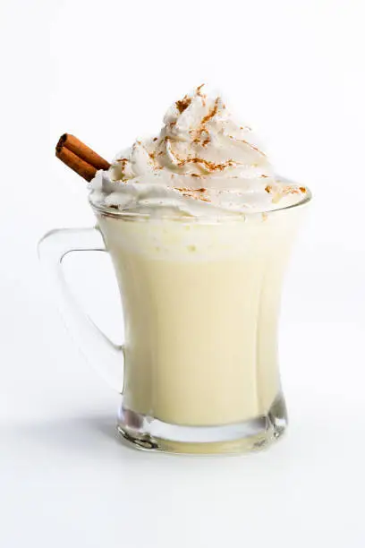 close up of a refreshing and sweet holiday treat, eggnog with whipped cream and cinnamon isolated on a white background