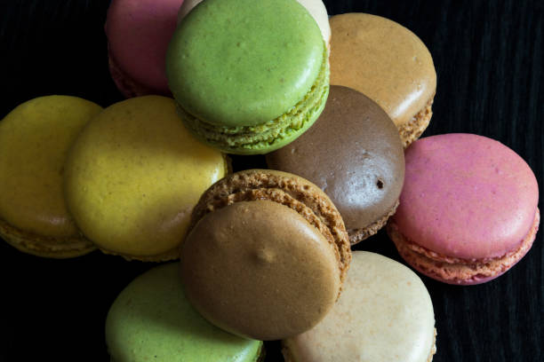 istock Macaroons of different colors in heaps on a dark background 915311476