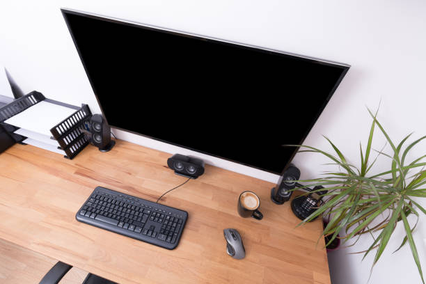 istock Large 4k screen in a home office with keyboard and equipment 915315948