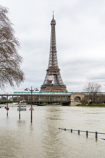 View of the swollen Seine during the winter flooding episode of January 2018, with the flooded expressway in the foreground and the Eiffel tower and Bir-Hakeim bridge in the background.
